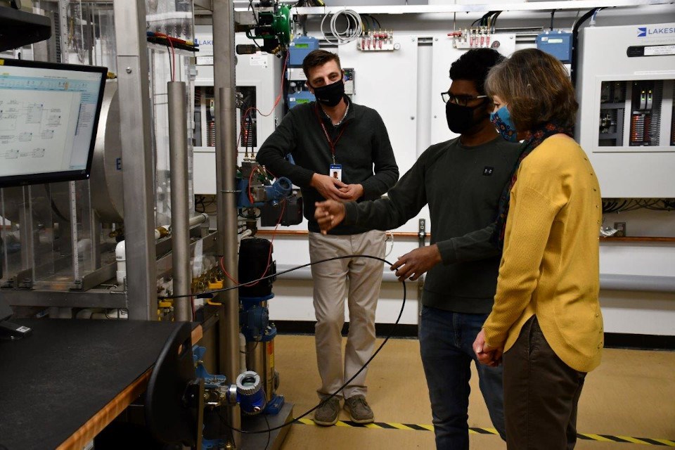 Student Sachin Raj Sampath (centre) demonstrates instrumentation equipment for Confederation College President Kathleen Lynch and Lakeside Team Lead of Regional Services Chris Foulds. 